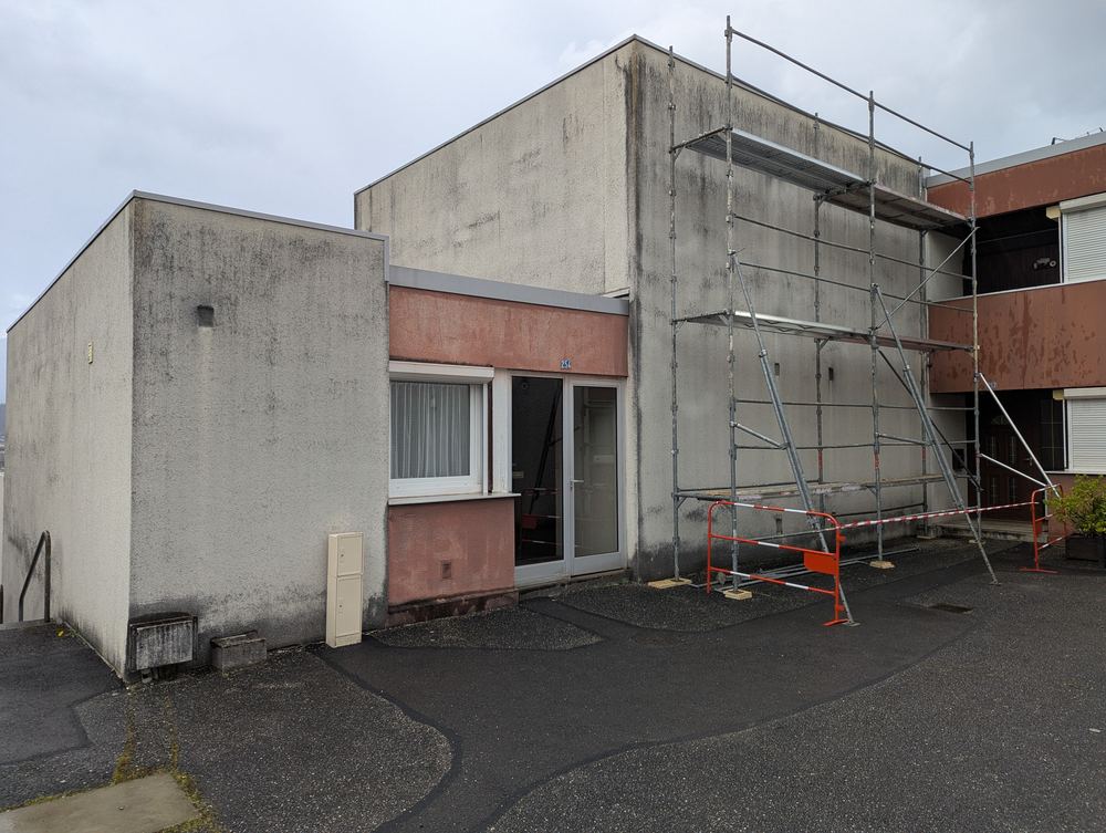 Façade à Chambéry avant ravalement : enduit gris noirci par les micro-organismes, échafaudage en place